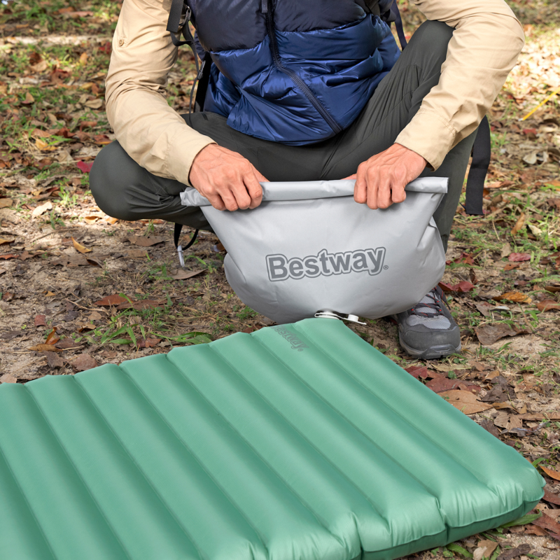 Camping-Isomatte auf dem Boden, grün, gerippte Luftkammern; unten Logo sichtbar